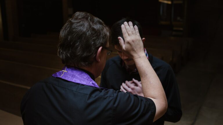 priest touching man's forehead